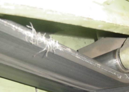 Caterpillar kayış kenarından dışarı çıkmış hasarlı kord lifleri